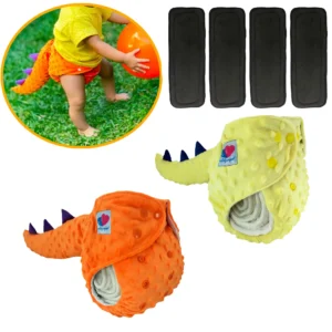 Dos pañales ecológicos reutilizables de tela Minky con cola de dinosaurio en colores naranja y amarillo, junto a cuatro insertos absorbentes negros y un bebé usándolo en el jardín.