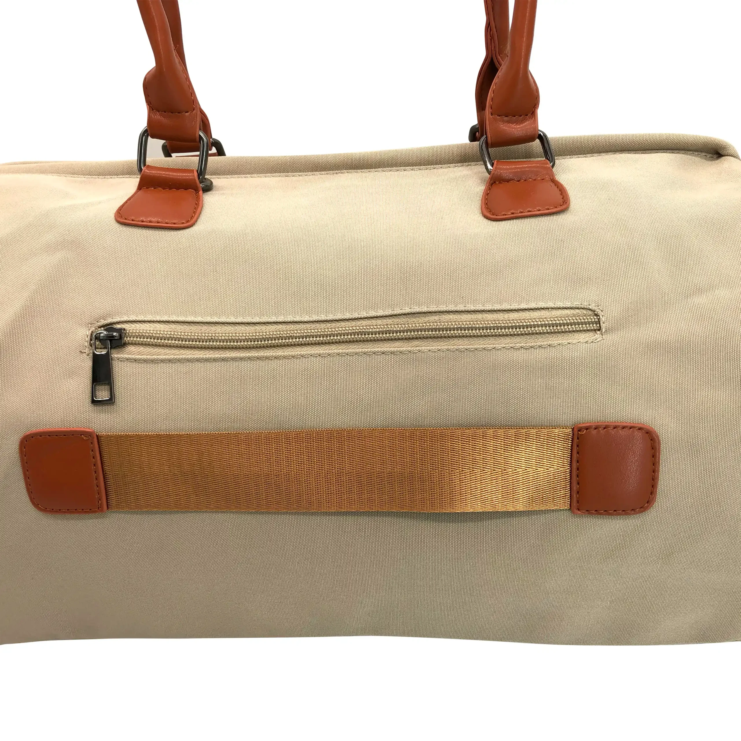 Primer plano de la parte trasera del bolso pañalera beige. Muestra a detalle un bolsillo horizontal con cierre de cremallera metálica oscura y, justo debajo, una banda o correa horizontal de nailon marrón reforzada con soportes de cuero sintético para sujetar el bolso a una maleta de viaje.