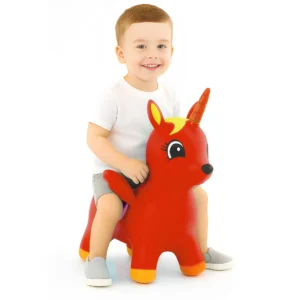 Niño sonriendo montado sobre un juguete inflable saltarín de unicornio color rojo con cuerno naranja y detalles amarillos, sobre un fondo blanco.