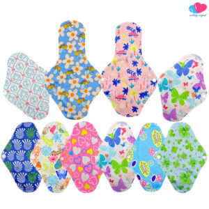 Kit de diez toallas sanitarias ecológicas de tela reutilizables de la marca EcoBaby Original dispuestas sobre fondo blanco. En la fila superior se observan dos toallas largas de modelo nocturno y dos toallas de modelo regular inclinadas en los extremos. En la fila inferior se alinean horizontalmente seis toallas regulares. Los estampados incluyen abejas con flores, mariposas, corazones, tréboles de la suerte, abanicos azules y diseños florales abstractos. El logotipo de la marca aparece en la esquina superior derecha.